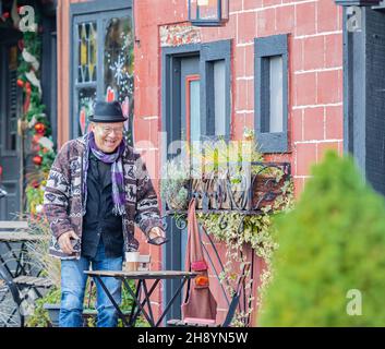 Glücklicher älterer Mann, der seinen Kaffee im Café im Freien genießt. Älterer, eleganter Mann, der sich im Café entspannt und Kaffee getrunken hat. Stockfoto
