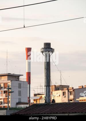 Foto des Panoramas der Schimpanoramen, aufgenommen in belgrad, Serbien: Vor dem Bild ist ein einzelner Metallkamin zu sehen, eine industrielle rot-weiße Fabrik Stockfoto