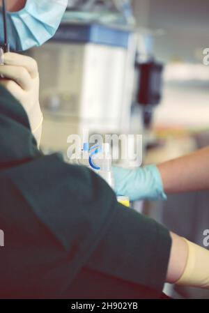 Ärzte, die den Patienten vor der Operation im Operationssaal an den künstlichen Lungenventilationsapparat anschließen. Stockfoto