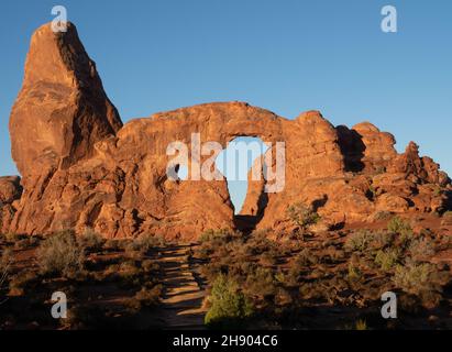 Die Silhouette einer Person, die bei Sonnenaufgang im Turret Arch im Arches National Park, Utah, steht. Stockfoto