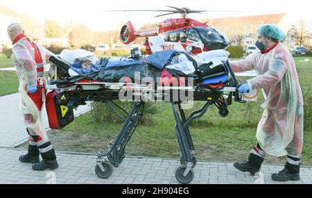 Wittenberg Lutherstadt, Deutschland. 02nd Dez 2021. Von der Corona-Intensivstation des Evangelischen Krankenhauses Paul Gerhard Stift wird eine an Covid 19 erkrankt Schwangere von Air Rescue-Notarzt Alexander Kampe (r) und Notarzthelferin Mario Gustke zum DRF-Hubschrauber gebracht. Aus medizinischen Gründen wird die Frau in das Pränatalzentrum des Universitätsklinikums Halle verlegt. Das Krankenhaus in Wittenberg hat seine sonst 10 Intensivstationen auf 16 erhöht, die derzeit alle belegt sind. Quelle: Waltraud Grubitzsch/dpa-Zentralbild/dpa/Alamy Live News Stockfoto