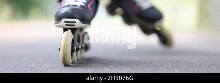 Kind fährt auf der Straße in Nahaufnahme auf schwarzen Rollerblades Stockfoto
