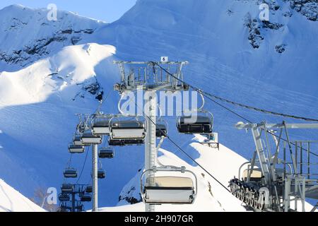 Eine leere Sessellift-Kabine. Im Hintergrund verschneite Pisten mit Spuren von Fans des Off-Piste-Skifahrens. Winterlandschaft des Skigebiets. Wintersport du Stockfoto