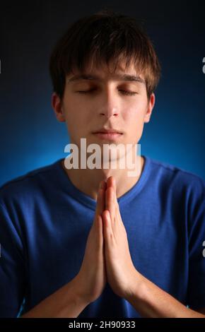 Junger Mann, der im dunklen Raum betet Stockfoto