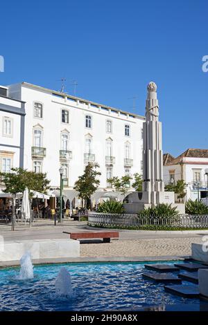 Frankreich Afrika-Kriegsdenkmal in der Praca de Republica mit Straßencafés hinten und einem Brunnen im Vordergrund, Tavira, Algarve, Portugal. Stockfoto