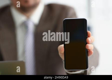 Männlicher Arm in Anzug zeigen in Kamera Handy-Display mit schwarzem Bildschirm Stockfoto