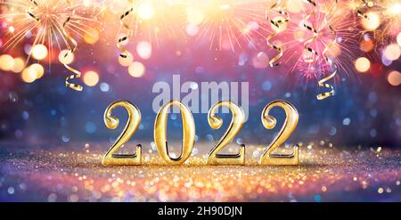 Neujahrsfeier 2022 - Goldene Zahlen Auf Glitzer Mit Feuerwerk Und Abstrakten Defokusskten Lichtern Stockfoto