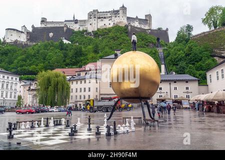 SALZBURG, ÖSTERREICH - 20. MAI 2019: Hier befindet sich ein Сathedral-Platz mit einem ungewöhnlichen Denkmal für einen Konditor auf einem Ballon und einem Blick auf die Burg Hohensalzburg Stockfoto