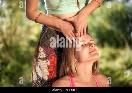 Mädchen Masseuse gibt ihrem Kunden eine erfrischende Massage auf dem Waldboden. Stockfoto