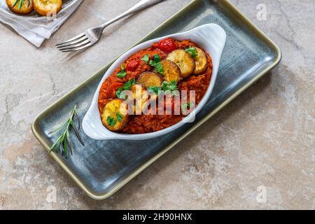 Reisjollof mit frittiertem Kochbananen - würziges vegetarisches afrikanisches Reisgericht Stockfoto