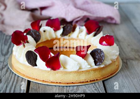 Mürbeteigherbe mit Beerenfüllung (Fruchtkühler, Kompott) und Chantilly-Creme (Schlagsahne), garniert mit Rosenblättern und Schokoladenscheiben. A bea Stockfoto