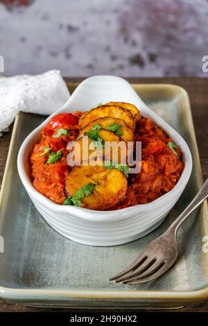 Reisjollof mit frittiertem Kochbananen - würziges vegetarisches afrikanisches Reisgericht Stockfoto