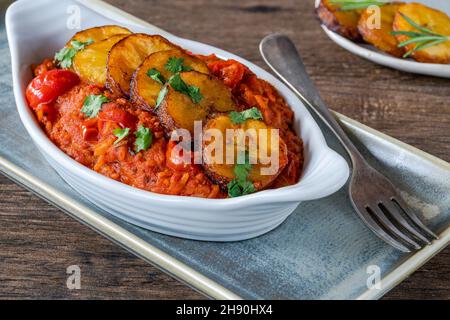 Reisjollof mit frittiertem Kochbananen - würziges vegetarisches afrikanisches Reisgericht Stockfoto