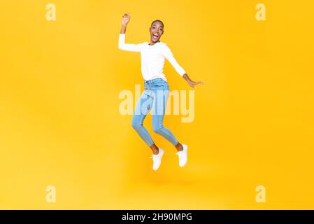 Energisch glücklich junge afroamerikanische Frau springen mit der Hand auf in isolierten gelben Studio Hintergrund Stockfoto