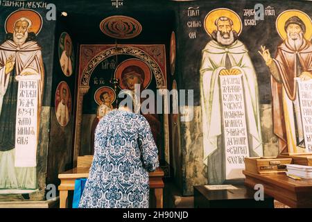 Frau betet vor den Ikonen im Kloster Ostrog. Montenegro Stockfoto