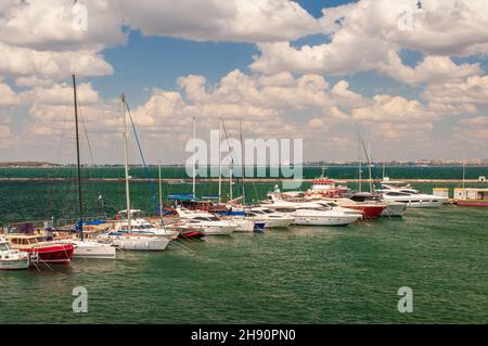 Odessa, Ukraine. 22. Juli 2021. Weiße Yachten liegen am Pier, das Meer ist smaragdgrün. In der Ferne sieht man den Wellenbrecher und die Stadt Stockfoto