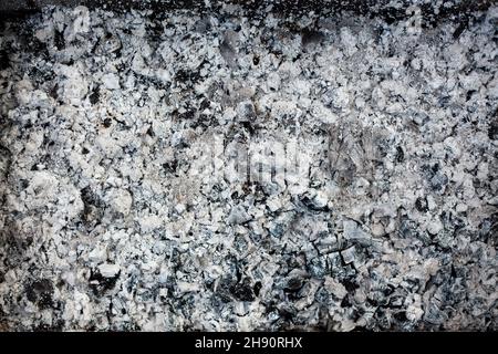 Hintergrund der Ash-Textur. Holzasche im Kamin. Defokussierte Kohlefaserstruktur. Verschwommener Schwarzweißhintergrund. Nahaufnahme Stockfoto