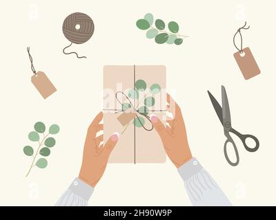 Braune weibliche Hände halten Geschenkbox in Kraftpapier verpackt. Draufsicht umweltfreundliche Verpackung, Eukalyptus, Schere, Anhänger. Öko Weihnachten und Neujahr Vorbereitung Stock Vektor