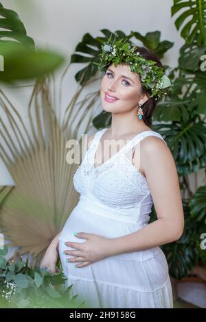 Attraktive Schwangeren in grünen Blättern Kranz Stockfoto