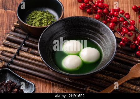 Nahaufnahme des großen Matcha tangyuan (tang Yuan) mit süßer Matcha-Suppe in einer Schüssel auf Holztischhintergrund für Festessen. Stockfoto