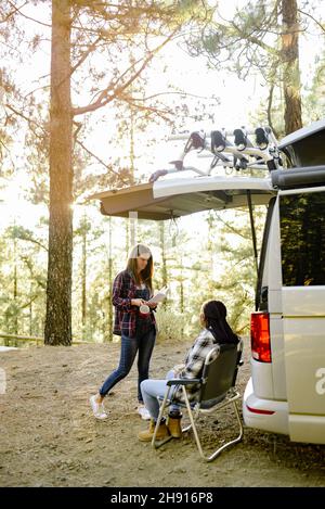 Verschiedene Reisende Frauen in der Nähe Wohnmobil im Wald Stockfoto