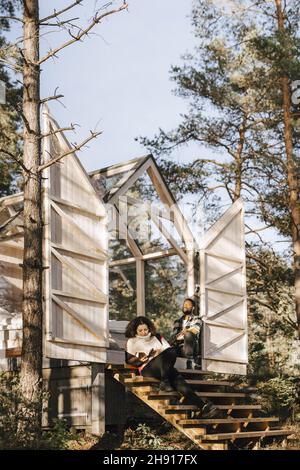 Pärchen sitzt auf Stufen der Hütte im Wald Stockfoto