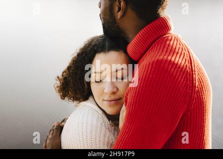 Junge Frau mit geschlossenen Augen umarmt Freund Stockfoto