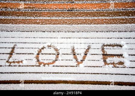 Das Wort LIEBE im Schnee auf einer Bank in einem Winterpark geschrieben Stockfoto