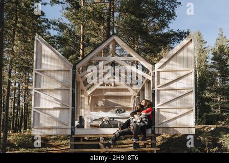 Ein Paar umarmte sich, während es auf dem Eingang der Hütte saß Stockfoto