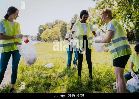 Lächelnde freiwillige Helfer beim Reinigen von Kunststoffen Stockfoto