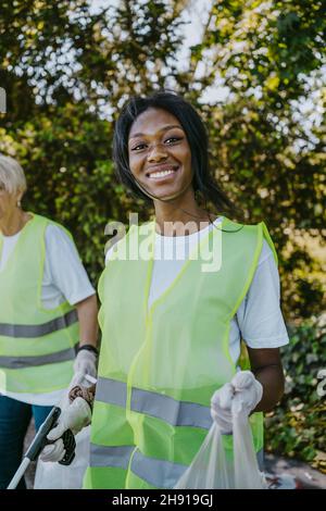 Porträt einer lächelnden Umweltschützerin mit Plastiktüte Stockfoto