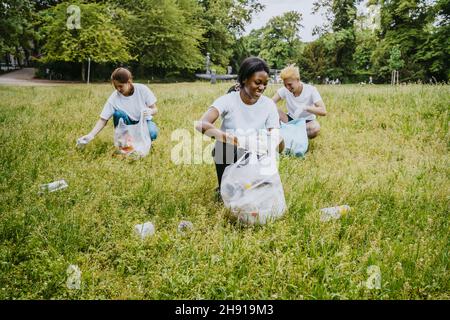 Lächelnde männliche und weibliche Freiwillige, die im Park Plastik abholen Stockfoto