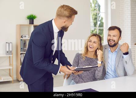 Junge Familie ist aufrichtig glücklich und feiert die Unterzeichnung des Kaufvertrages oder die Genehmigung des Darlehens. Stockfoto