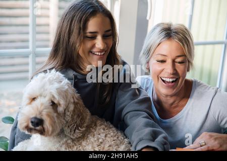 Glückliche Tochter und Mutter mit Hund zu Hause Stockfoto