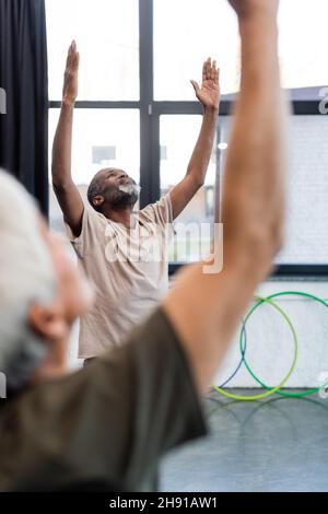 Lächelnder afroamerikanischer Mann, der in Yoga-Pose im Sportzentrum steht Stockfoto