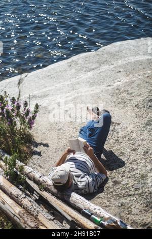 Blick aus der Höhe auf den Mann, der an einem sonnigen Tag auf der Insel ein Buch liest Stockfoto