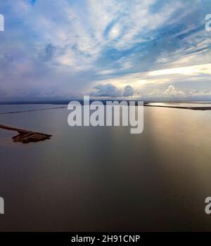 Luftaufnahme des frühen Morgens bei Sonnenaufgang. Die Seeoberfläche, die zwischen Sumpfland und Himmel mit dramatischen Wolken versperrt ist Stockfoto