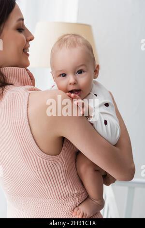 Kleinkind Junge Blick auf Kamera in den Händen der Mutter zu Hause Stockfoto