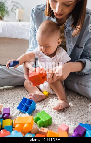 Kleinkind Sohn mit Mutter spielt mit bunten Bausteinen des Bodens Stockfoto