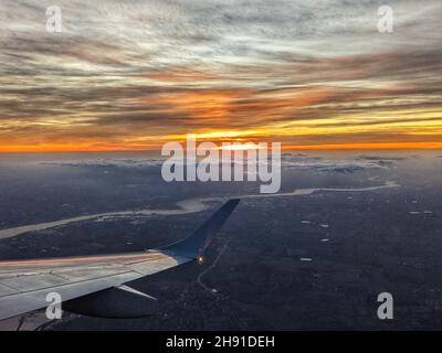 Die Sonne geht in einem orangefarbenen Himmel über London unter, wobei die Themse auf diesem Foto aus einem Flugzeug deutlich sichtbar ist. Stockfoto
