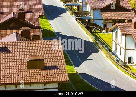 Aero Blick auf braune Ziegeldächer mit Ziegelrohren von zweistöckigen Häusern gepflasterte Straße Stockfoto