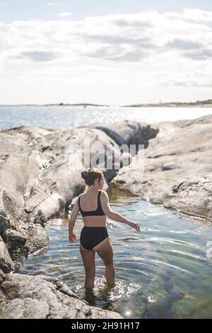 Frau mittleren Erwachsenen, die im Urlaub im Meer spazieren geht Stockfoto