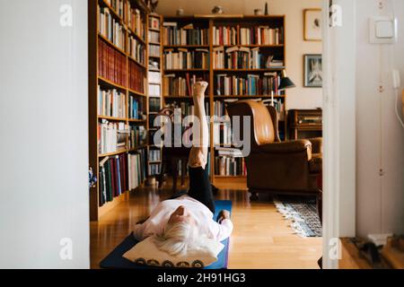 Ältere Frau macht Beinübungen im Wohnzimmer Stockfoto