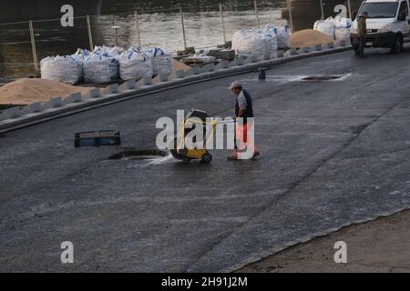 Budapest, Ungarn - 1. November 2021: Arbeiter in einheitlichem Asphalt mit Maschinen auf dem Damm, illustrative Editorial. Stockfoto