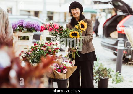 Lächelnde ältere Frau, die Blumen vom Markt kauft Stockfoto