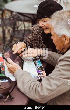 Ältere Männer und Frauen nutzen GPS-Navigation durch digitales Tablet am Tisch Stockfoto