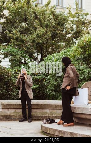 Älterer Mann fotografiert am Wochenende eine Frau im Park Stockfoto