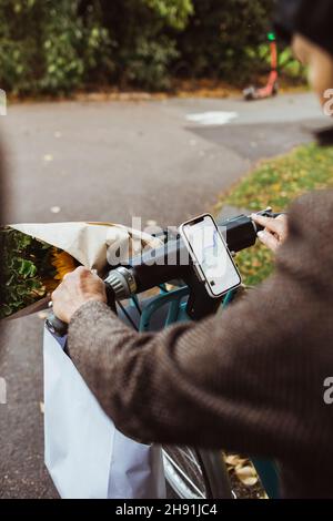 Zugeschnittenes Bild einer älteren Frau, die auf der Straße mit einem Elektrofahrrad unterwegs ist Stockfoto