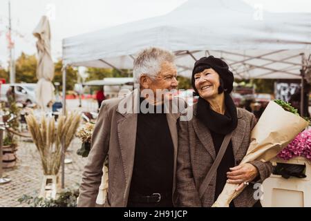 Fröhliches Seniorenpaar, das während des Urlaubs auf dem Markt spazieren ging Stockfoto