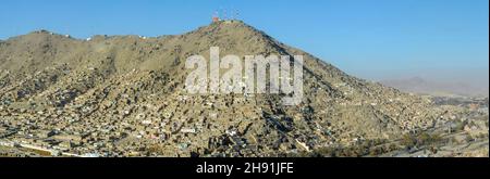 Luftaufnahme einer informellen Siedlung am Hang von Kabul in Afghanistan mit Sendetürmen auf dem Gipfel des Berges in weiter Ferne Stockfoto